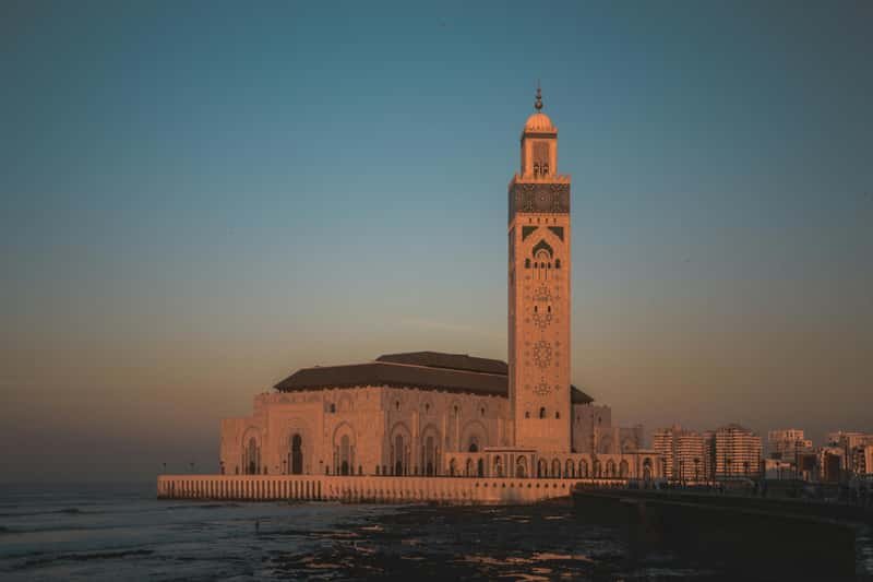 Hassan II Mosque silhouette against orange sunset sky in Casablanca Morocco