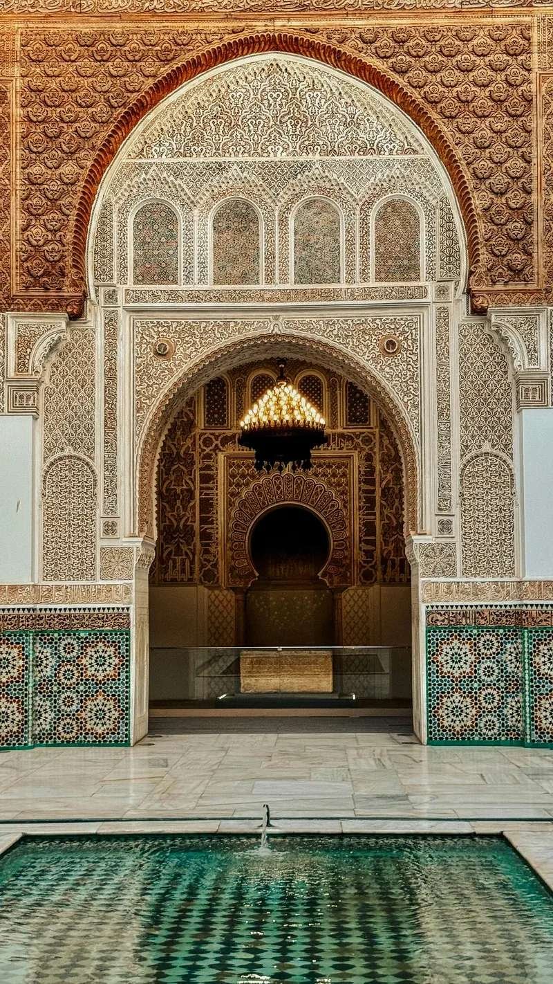Exquisite palace interior in Marrakech with ornate zellige fountain, intricate carved plaster ceiling, and traditional Moroccan craftsmanship