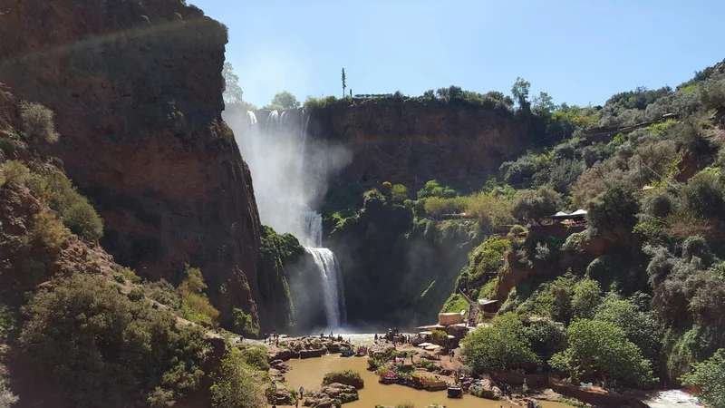 Spectacular Ouzoud Falls cascading through lush green gorge with visitors at the base in Morocco